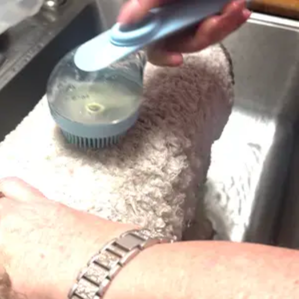 Washing a fluffy dog with the PawSuds brush in the sink